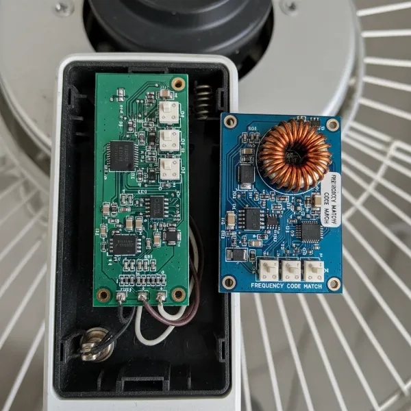 Close-up of a fan remote control and a fan receiver, both showing matching dip switch settings.